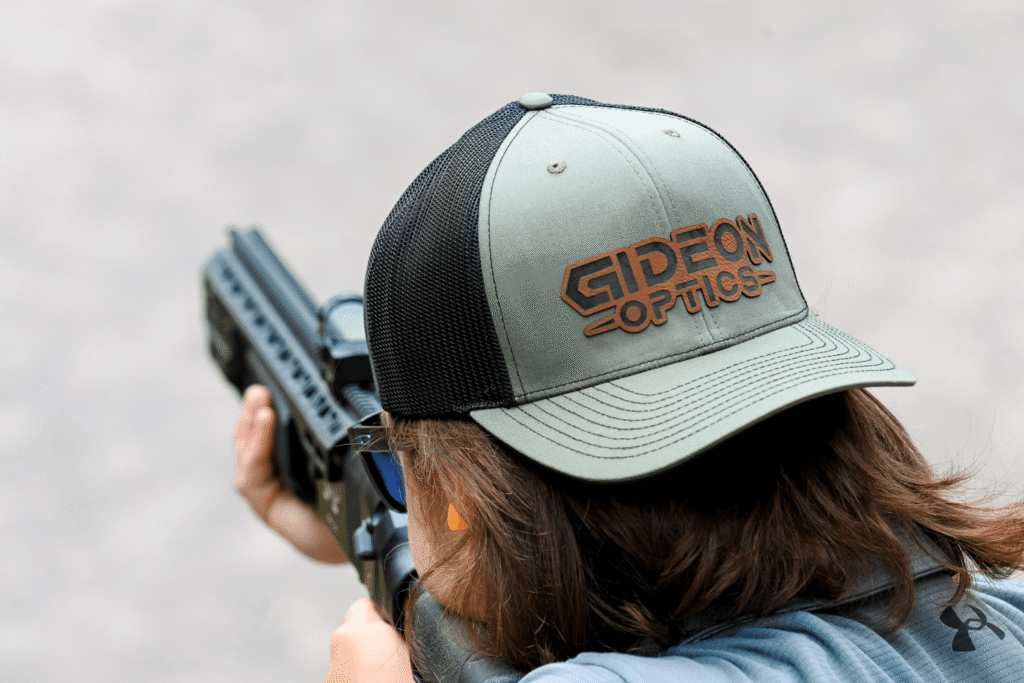 AR at shooting range - JSD Supply | Premier Gun Parts And Accessories man wearing a backwards baseball cap aiming an AR-style firearm at a shooting range