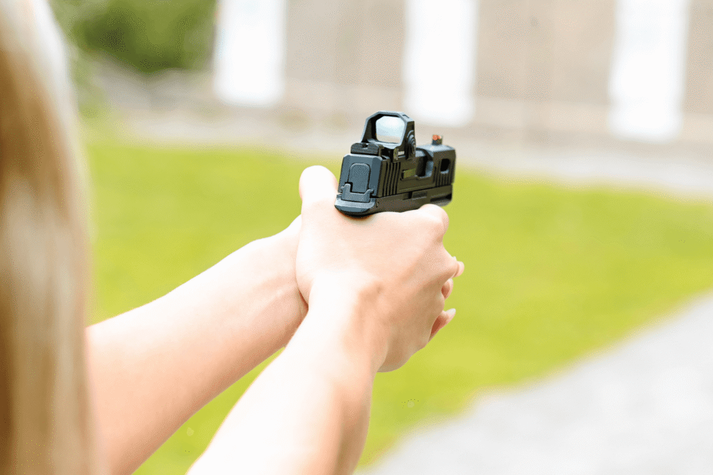 hands holding a pistol with an optic mounted