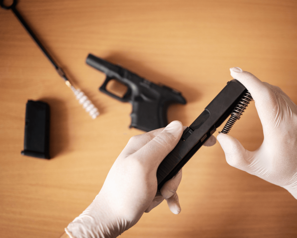 image - JSD Supply | Premier Gun Parts And Accessories hands wearing white gloves hold a pistol slide from a disassembled firearm