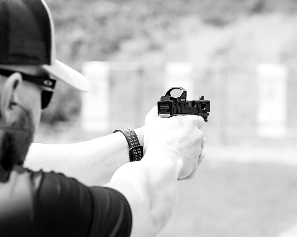 View from behind a man firing a handgun at a shooting range