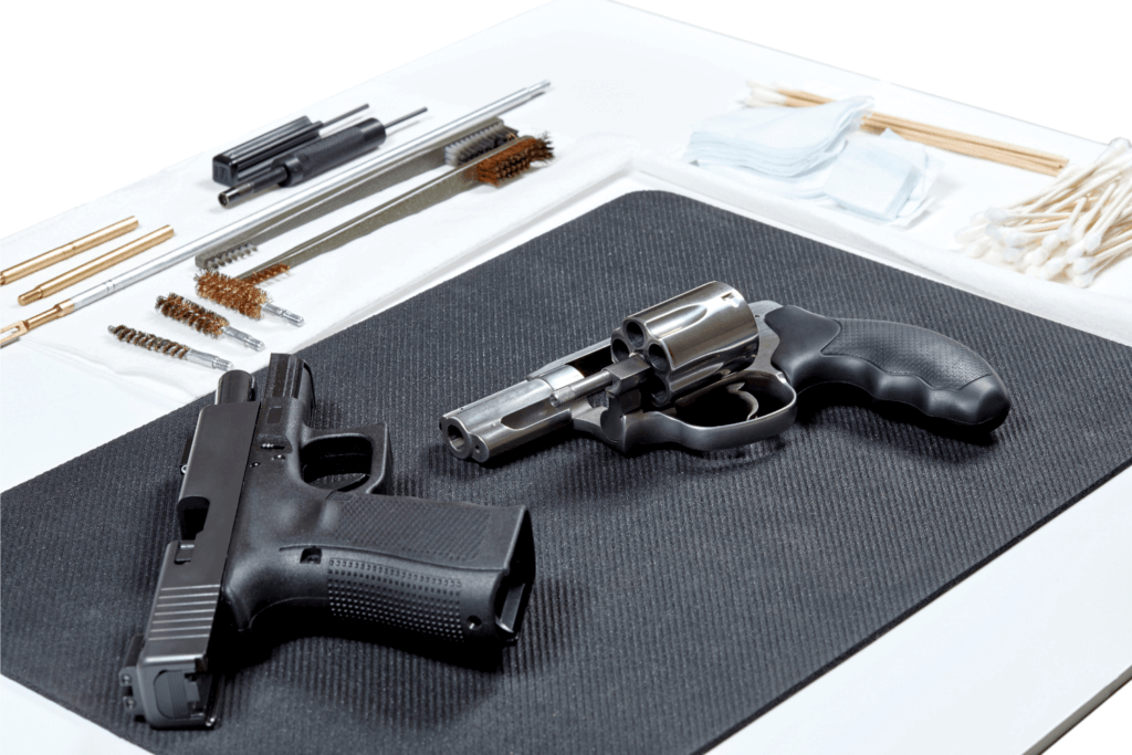 A revolver and handgun laying on a pad in preparation for a cleaning
