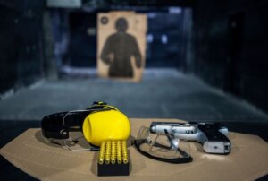 Protective gear, ammunition, and a firearm sitting on a booth at an indoor shooting range