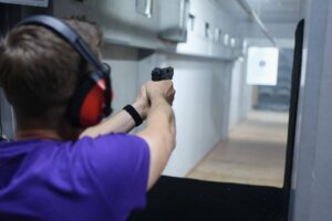 Man at an indoor shooting range aiming his pistol at a target