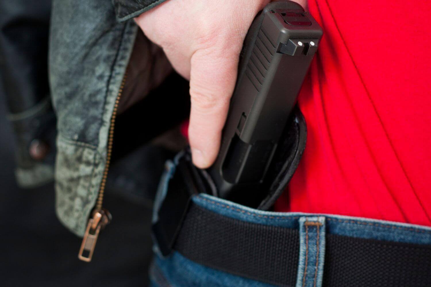 A man drawing his firearm from his concealed carry holster