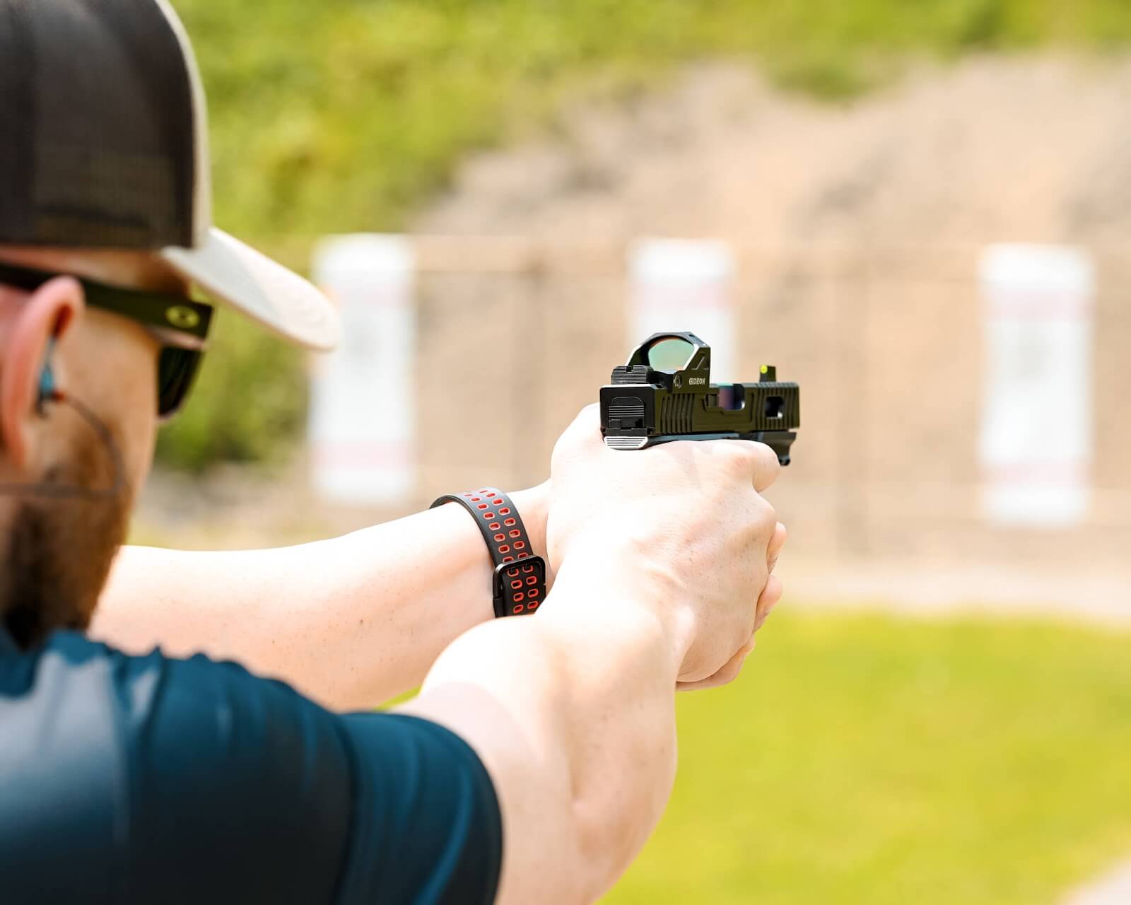 Man aiming a firearm with a red dot sight mounted 