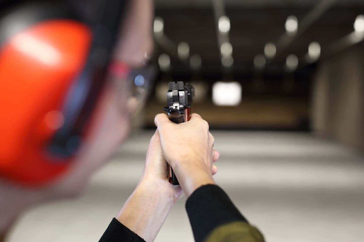 Woman at a shooting range aiming her firearm at a target