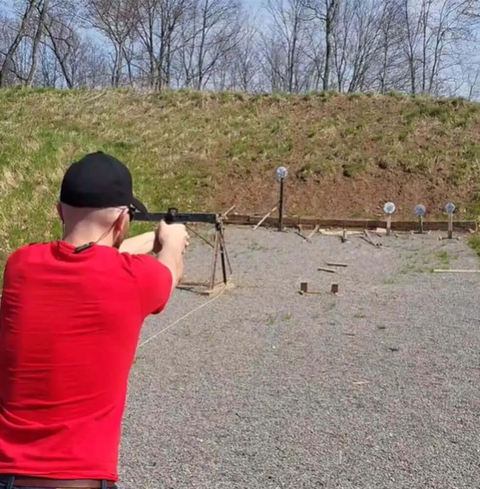 Man at an outdoor shooting range firing a gun with a pull-release trigger installed