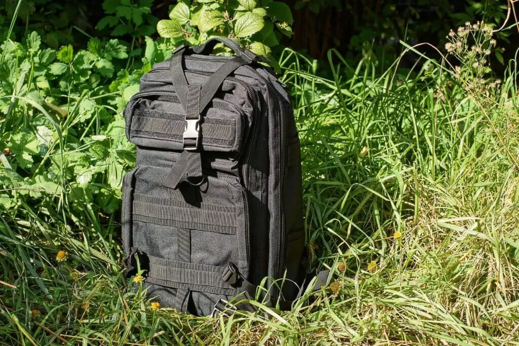 Black tactical gun range bag sitting in the grass