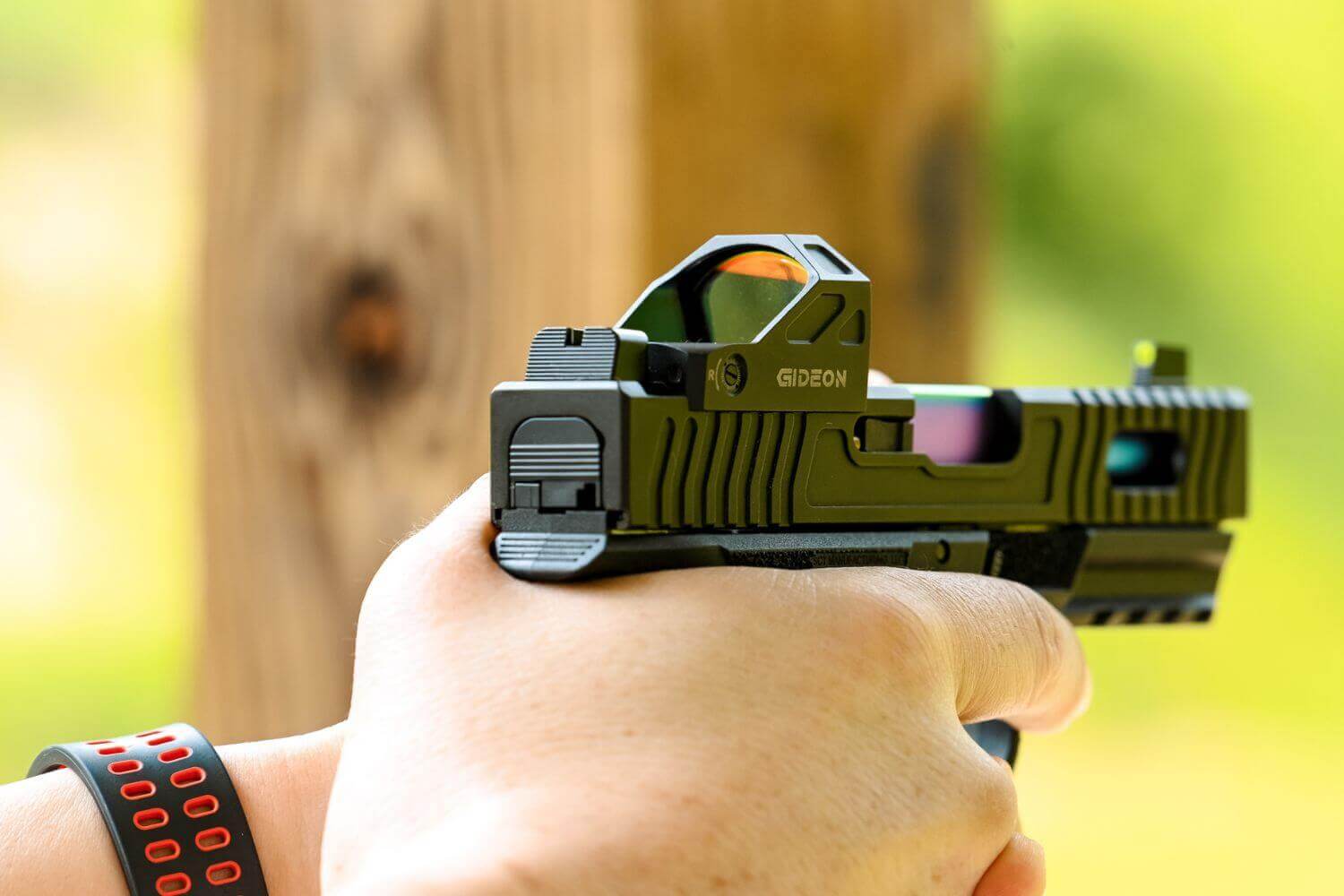 man aiming a pistol with a red dot sight mounted