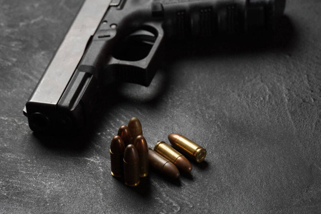 Black gun lying on a table with bullets