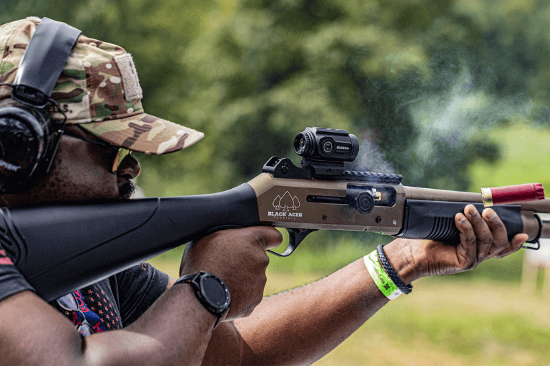 Man shooting a shotgun with a Gideon optics red dot sight mounted
