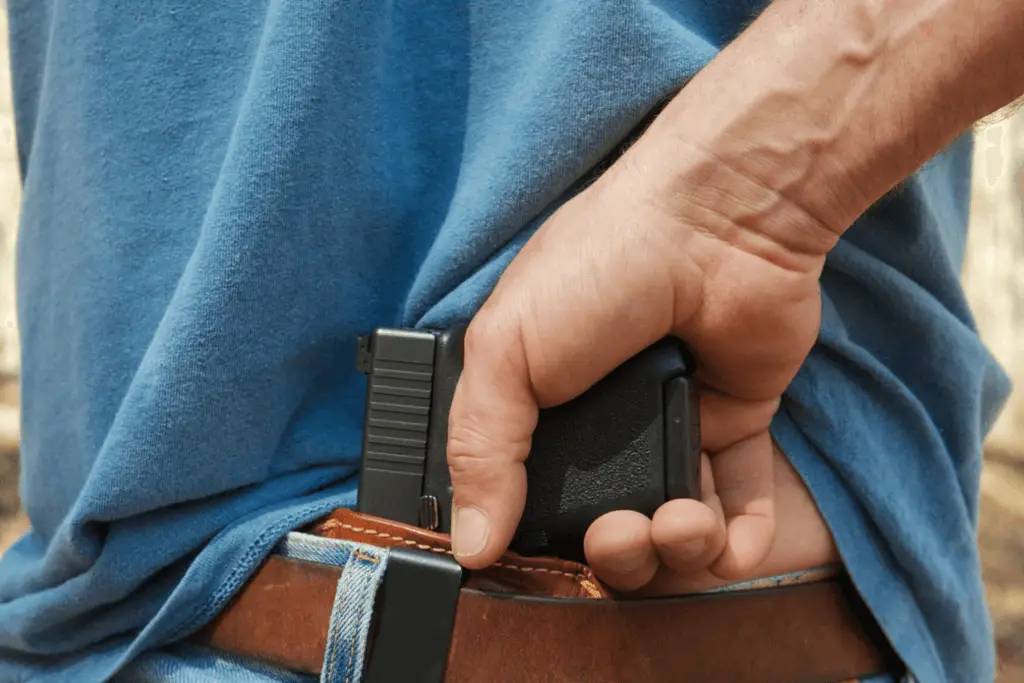 Man with his hand on his pistol that is secured in his waistband holster