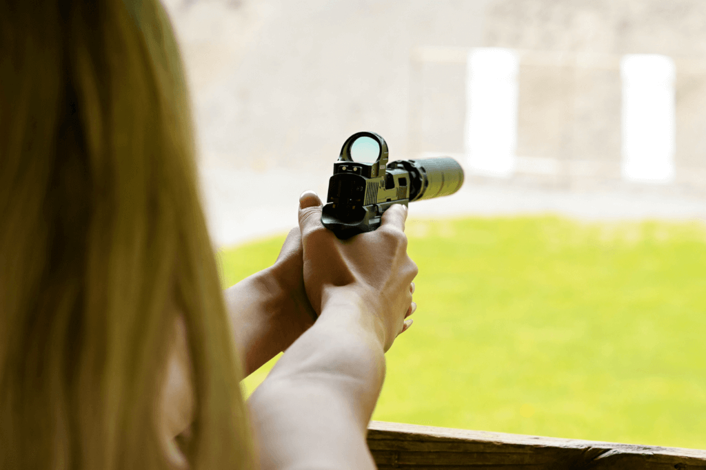 woman aiming a firearm during practice at an outdoor shooting range