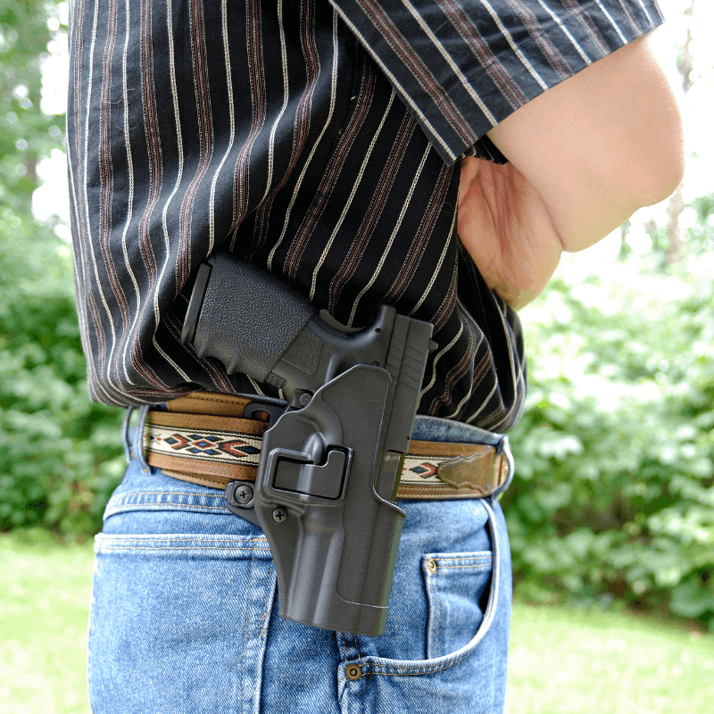 Man in blue jeans with a gun holster secured on his waistband - Premier Gun Parts And Accessories | JSD Supply Man in blue jeans with a gun holster secured on his waistband