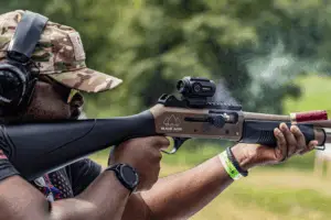Man at an outdoor shooting event firing a shotgun