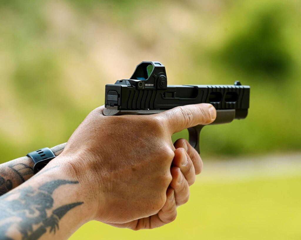 Hands aiming a firearm with an optic mounted