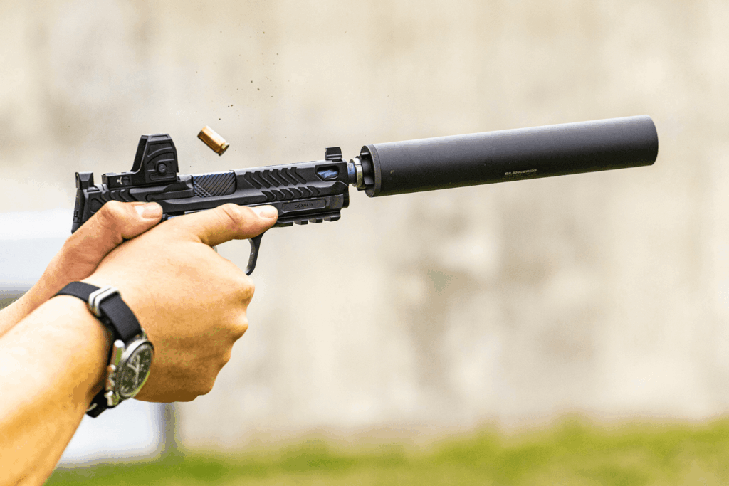 hands firing a pistol with a red dot optic mounted